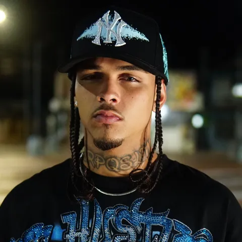 AM de noche en una calle de la ciudad, con una gorra de New York con strass y una camiseta de Hustlers