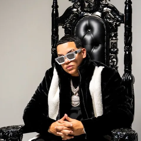 J Alvarez sentado en un trono negro tallado