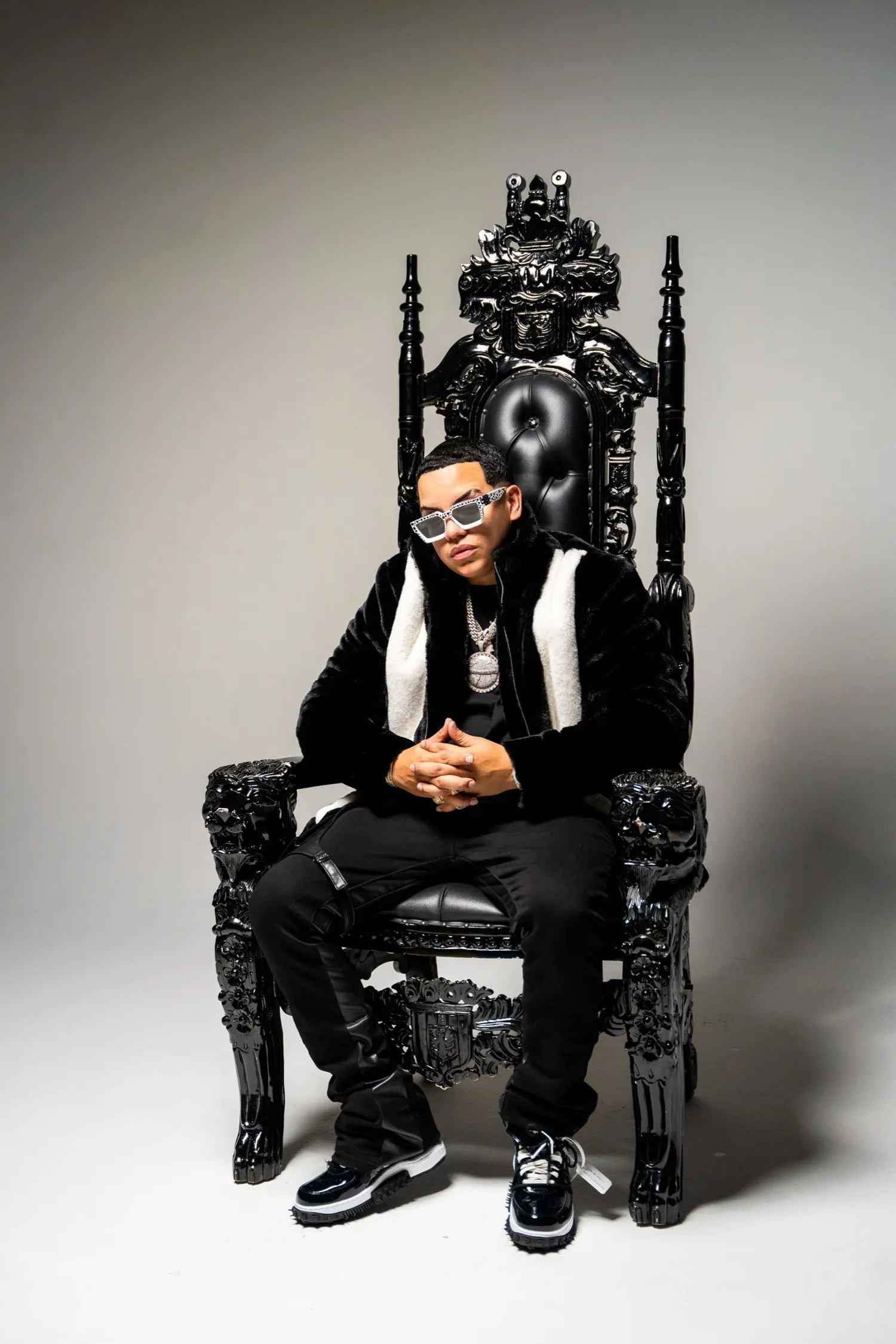 J Alvarez sentado en un trono negro tallado
