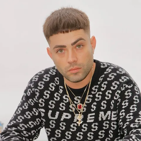 Markz sitting on a terrace in a dollar-sign sweater