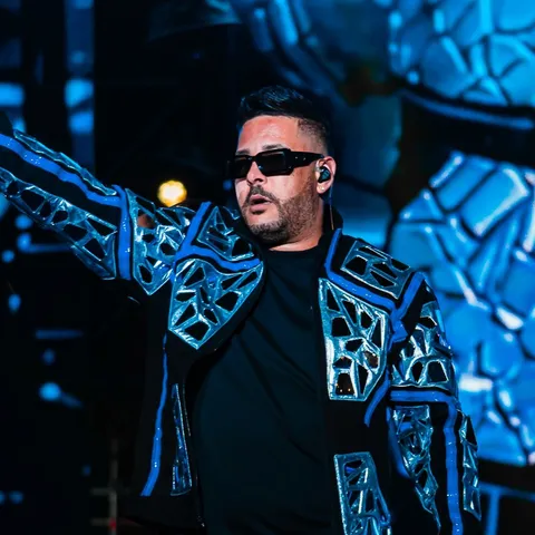 RKM performing on stage in a blue mosaic suit