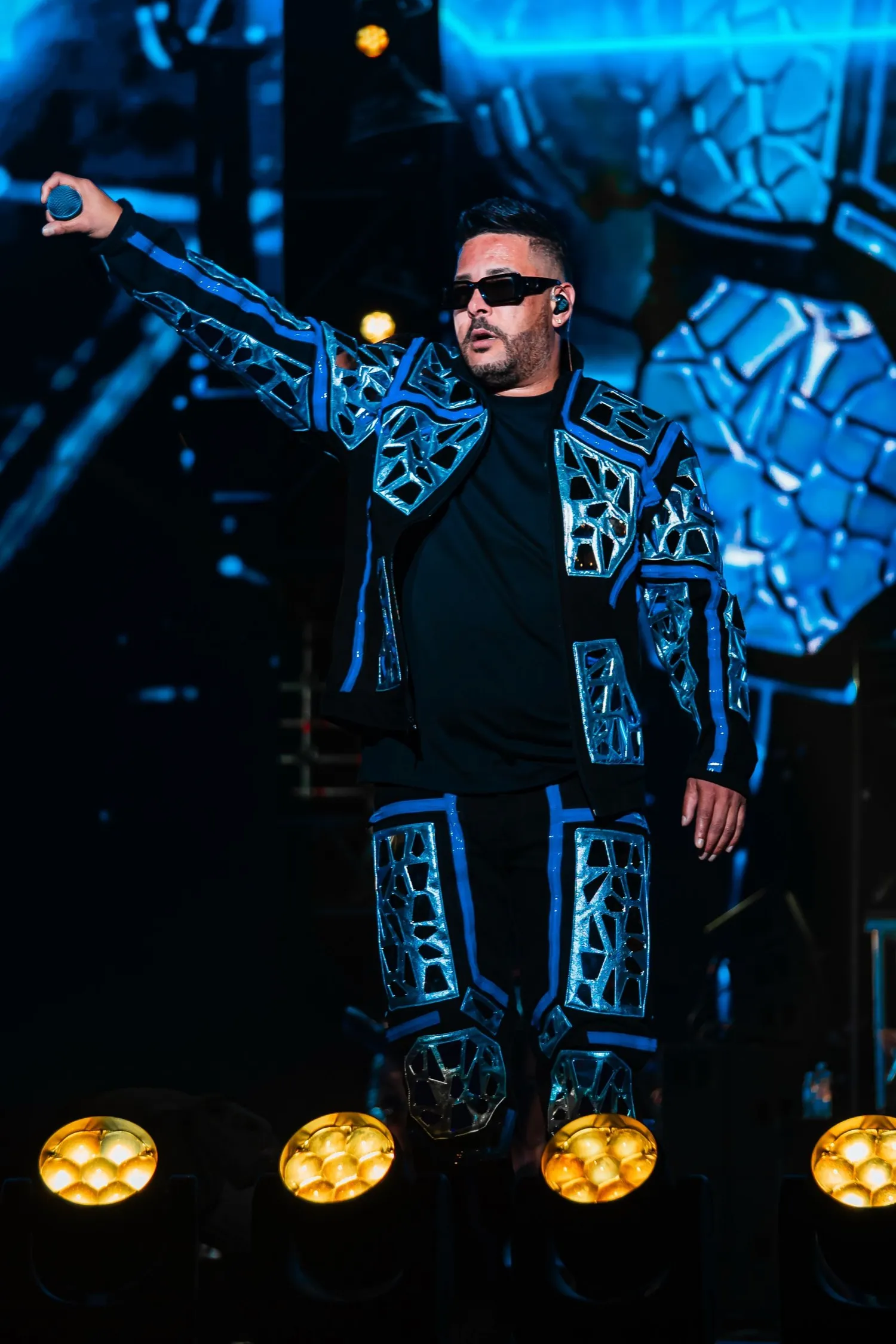 RKM performing on stage in a blue mosaic suit
